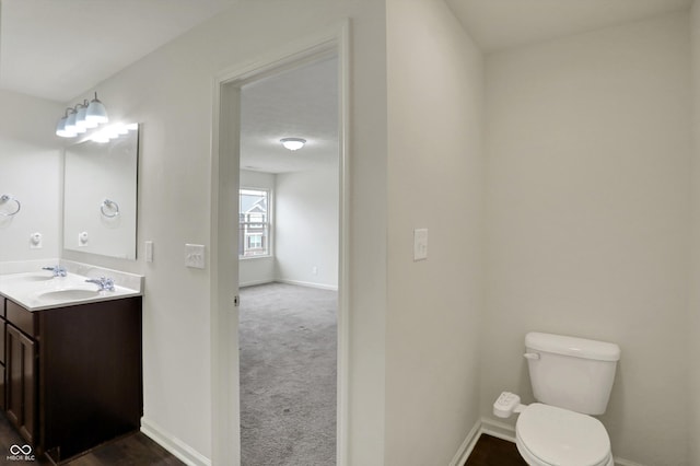 bathroom with toilet, double vanity, and baseboards