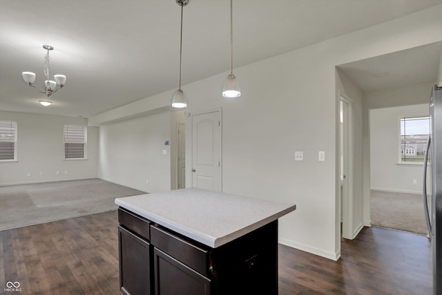 kitchen with a kitchen island, light countertops, hanging light fixtures, a notable chandelier, and dark wood-style floors