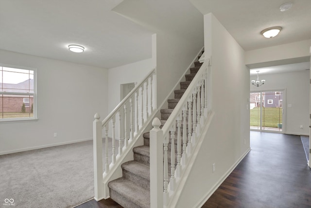 staircase with baseboards, an inviting chandelier, and wood finished floors