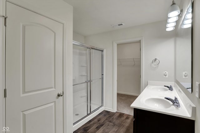 full bath with a sink, visible vents, a shower stall, and wood finished floors