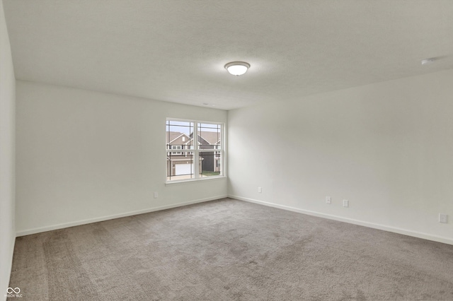 spare room with carpet, baseboards, and a textured ceiling