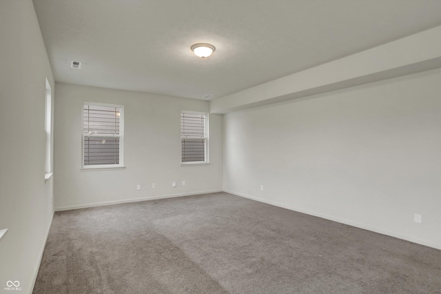 carpeted empty room with visible vents, baseboards, and a textured ceiling