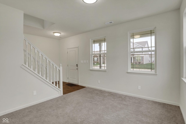 entrance foyer with dark carpet, baseboards, stairway, and visible vents