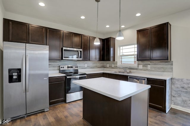 kitchen with appliances with stainless steel finishes, a sink, dark wood finished floors, and dark brown cabinetry