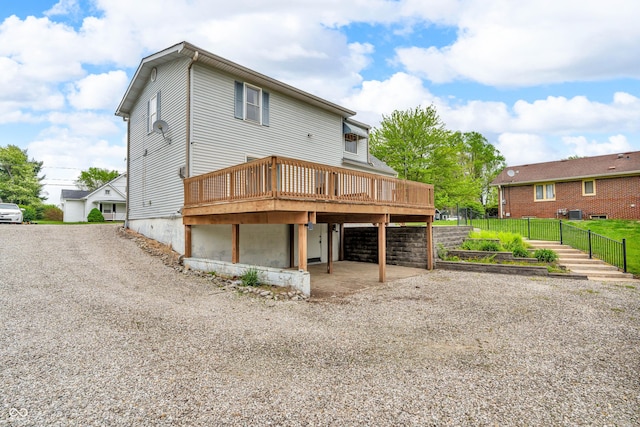 back of house featuring a deck, a carport, and gravel driveway