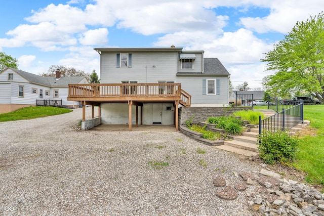 rear view of property featuring fence, a wooden deck, a carport, and gravel driveway