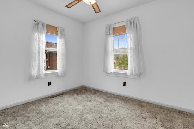 carpeted spare room with ceiling fan, visible vents, and baseboards