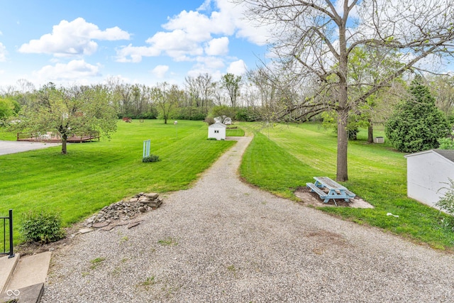 surrounding community with a lawn, gravel driveway, an outbuilding, and a storage unit