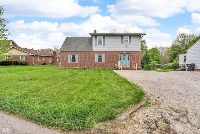 view of front of property with brick siding, driveway, a chimney, and a front yard