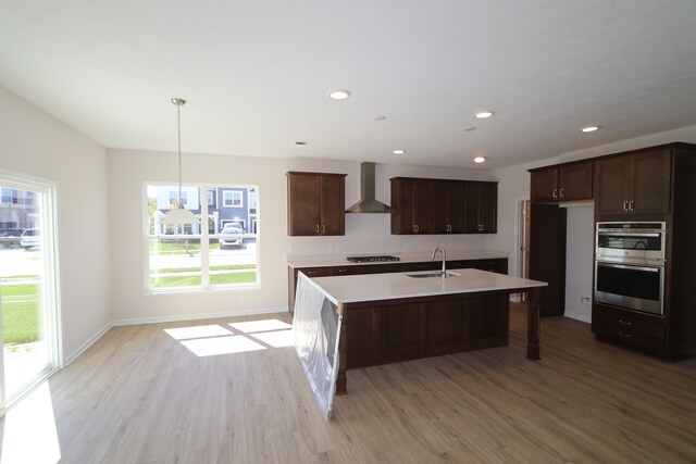 10543 Banyan Wood Ct, Indianapolis, IN 46239 - kitchen with wall chimney exhaust hood, a sink, light wood-type flooring, double oven, and light countertops