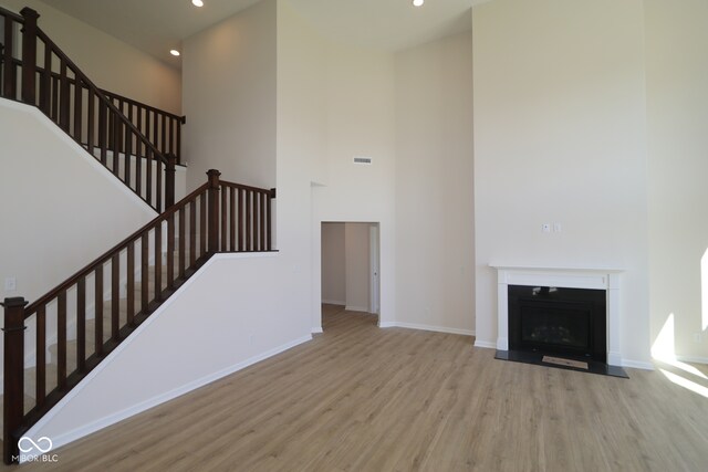 10543 Banyan Wood Ct, Indianapolis, IN 46239 - unfurnished living room with wood finished floors, a towering ceiling, stairway, baseboards, and recessed lighting