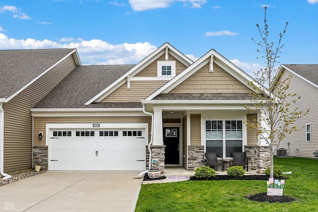 craftsman-style house with concrete driveway, an attached garage, a porch, a front yard, and stone siding