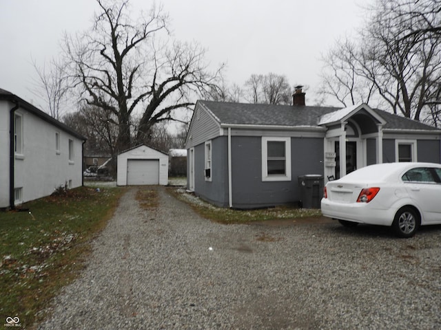 4920 E 34th St, Indianapolis, IN 46218 - view of side of home with a chimney, an outdoor structure, a detached garage, driveway, and roof with shingles