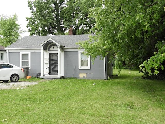 4920 E 34th St, Indianapolis, IN 46218 - view of front of home featuring a shingled roof, a front yard, a chimney, and concrete block siding