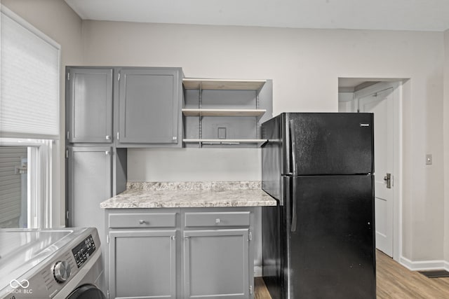 601 Wallace Ave, Indianapolis, IN 46201 - kitchen featuring washer / dryer, open shelves, freestanding refrigerator, and gray cabinetry