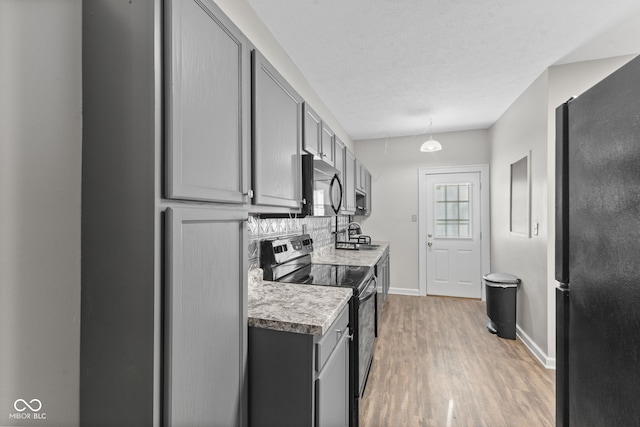 601 Wallace Ave, Indianapolis, IN 46201 - kitchen with light wood-type flooring, light countertops, gray cabinetry, decorative backsplash, and black appliances