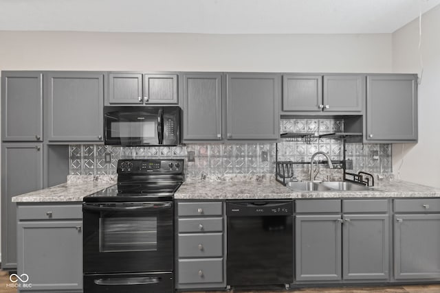 601 Wallace Ave, Indianapolis, IN 46201 - kitchen with light stone countertops, tasteful backsplash, black appliances, a sink, and gray cabinetry