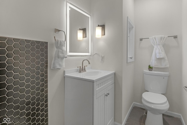 bathroom with toilet, vanity, baseboards, and tile patterned flooring