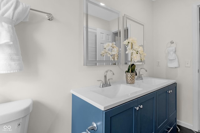 bathroom featuring a sink, toilet, and double vanity