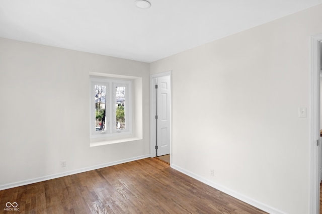 spare room featuring baseboards and wood finished floors
