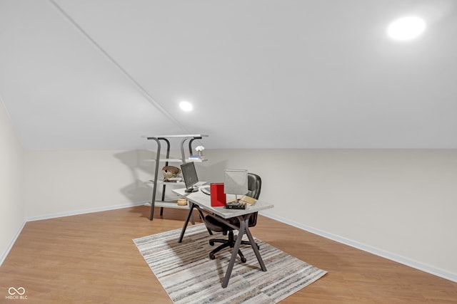 office space with baseboards, light wood finished floors, and vaulted ceiling