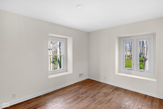 spare room featuring visible vents, baseboards, and wood finished floors