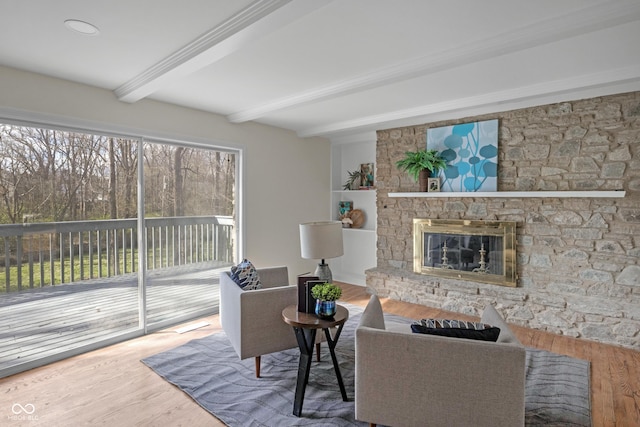 living area with a fireplace, beamed ceiling, and wood finished floors