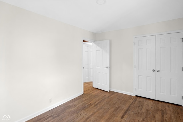 unfurnished bedroom with wood finished floors, baseboards, and a closet