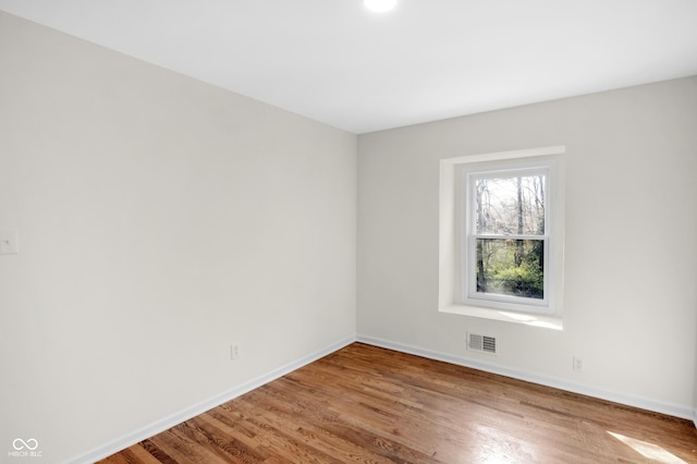 spare room featuring visible vents, baseboards, and wood finished floors
