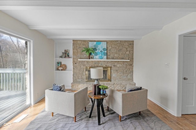 living area featuring beamed ceiling, plenty of natural light, and wood finished floors
