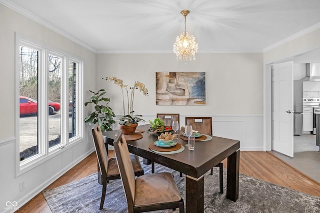 dining space with crown molding, light wood finished floors, and a notable chandelier
