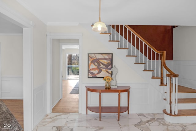 staircase with a decorative wall, marble finish floor, crown molding, and a wainscoted wall