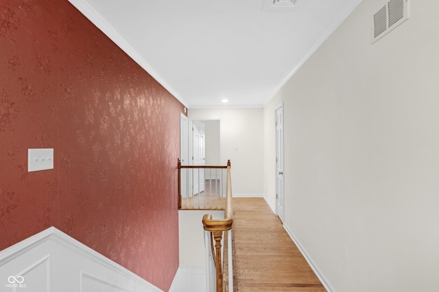 hallway with crown molding, visible vents, an upstairs landing, light wood finished floors, and baseboards