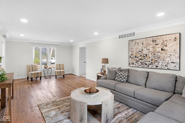 living room featuring visible vents, baseboards, ornamental molding, recessed lighting, and wood finished floors