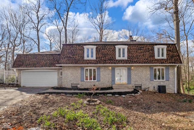 view of front of home featuring mansard roof, an attached garage, a chimney, a shingled roof, and driveway