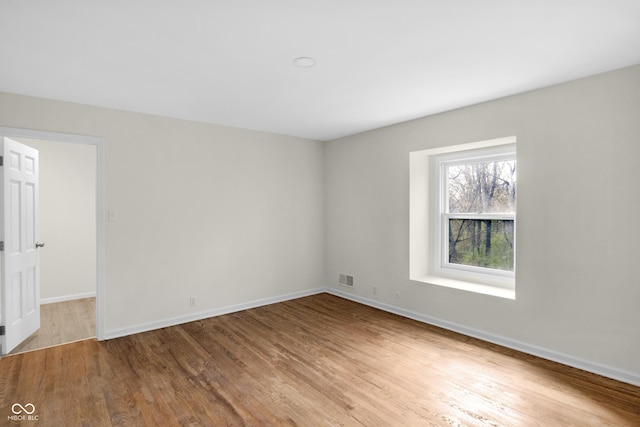 spare room with wood finished floors, baseboards, and visible vents