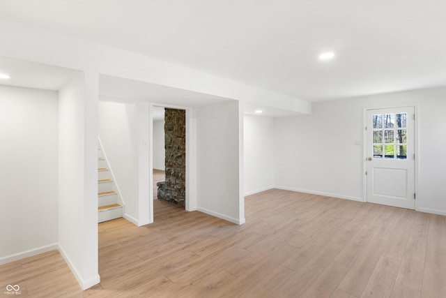 basement featuring light wood-type flooring, recessed lighting, baseboards, and stairway