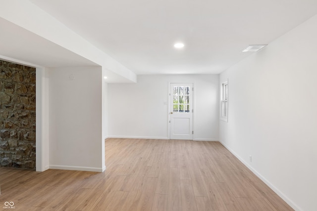 empty room featuring light wood finished floors, baseboards, and visible vents
