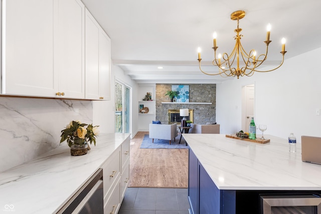 kitchen with tile patterned floors, white cabinets, a chandelier, and light stone countertops