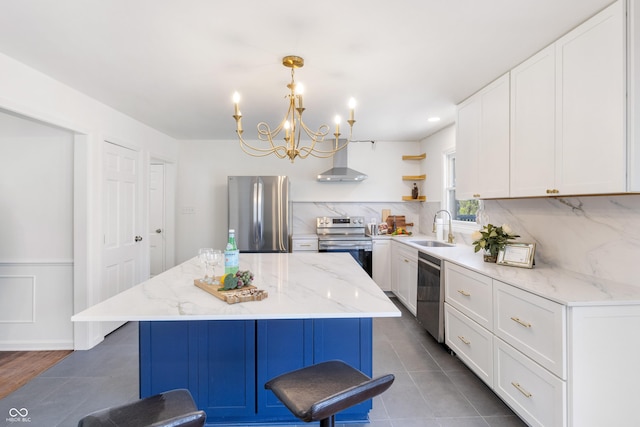 kitchen featuring open shelves, a notable chandelier, wall chimney exhaust hood, a sink, and appliances with stainless steel finishes