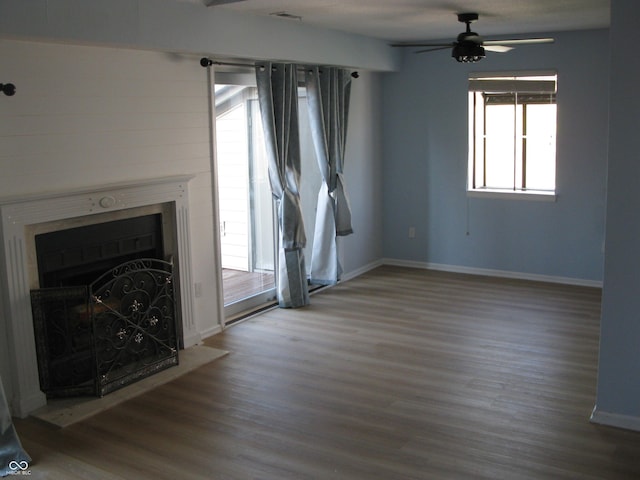 unfurnished living room featuring wood finished floors, ceiling fan, a fireplace, and baseboards