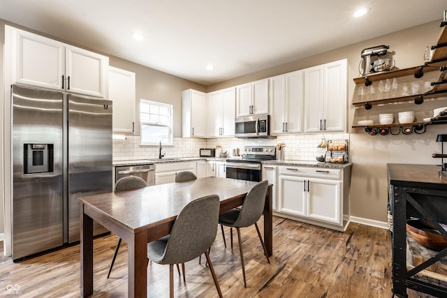 1603 E Market St, Indianapolis, IN 46201 - kitchen featuring light wood-style flooring, white cabinets, decorative backsplash, and stainless steel appliances