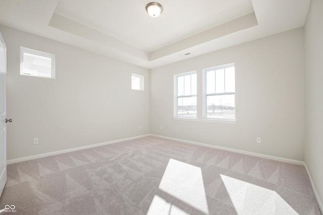 empty room featuring visible vents, a tray ceiling, baseboards, and light carpet