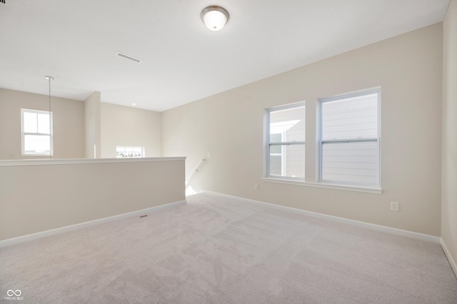 carpeted spare room with visible vents and baseboards