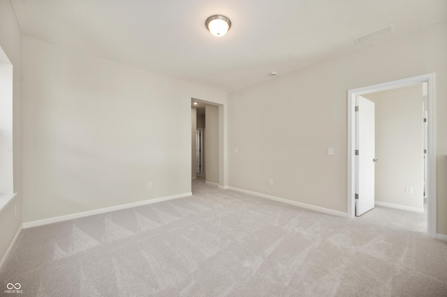empty room with visible vents, baseboards, and light carpet