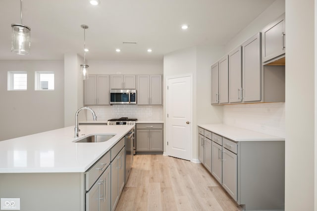 kitchen featuring light wood-type flooring, gray cabinetry, visible vents, stainless steel appliances, and a sink