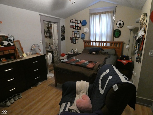 bedroom with light wood-style floors and lofted ceiling