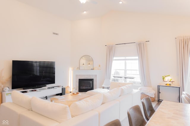 living room with high vaulted ceiling, a glass covered fireplace, and visible vents