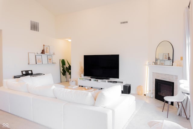 living area featuring a tiled fireplace, high vaulted ceiling, and visible vents
