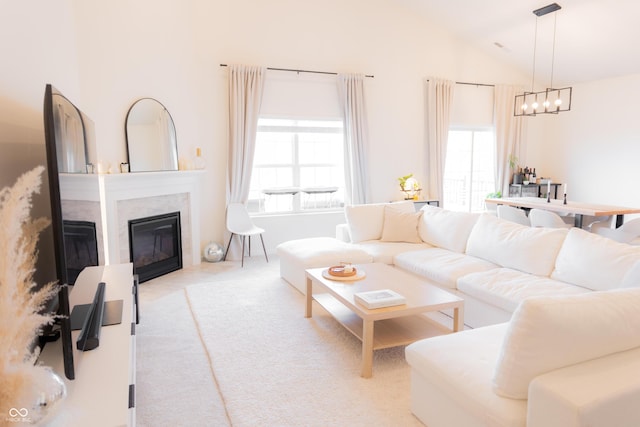 carpeted living room with lofted ceiling, a notable chandelier, and a premium fireplace